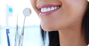 Dental mirror and instruments beside a smiling patient